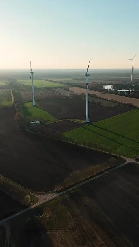 Vertical screen. Multiple wind turbines generating green energy across farmland Vídeo Stock 324637493