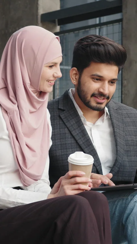 Vertical Screen: Muslim man and woman using laptop for work on stairs. Two Stock Footage 272832421