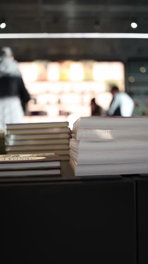 Vertical screen: A neatly stacked selection of books on a dark counter in a book Stock Footage 304459547