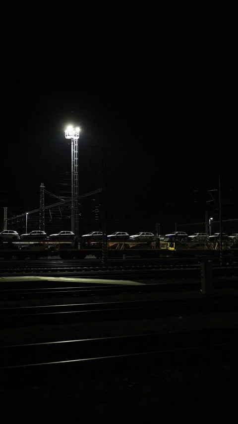 Vertical screen night railway yard illuminated by bright tower light with parked Stock Footage 319242251