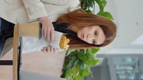 Vertical Screen: Office worker having lunch break and watching video on laptop Stock Footage 223489607
