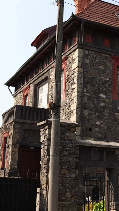 Vertical screen old stone house with red window frames and wooden details stands Stock Footage 314979112