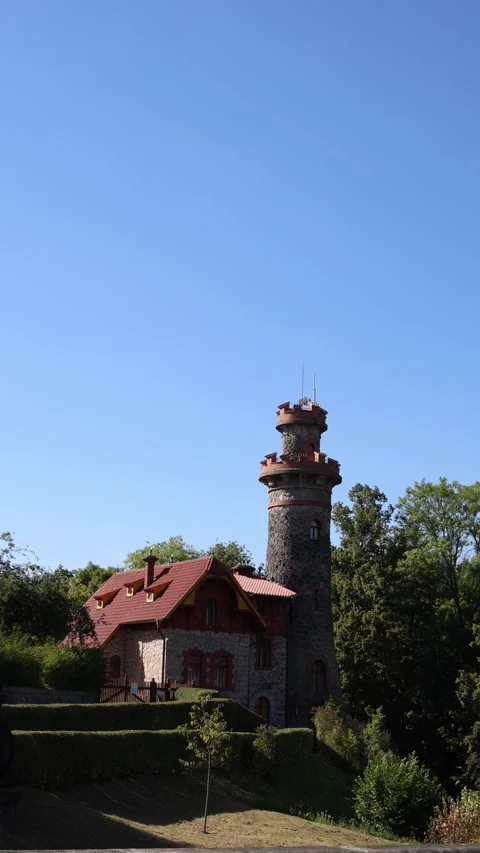 Vertical screen old stone tower with red roof standing beside a charming house s Stock Footage 315940015