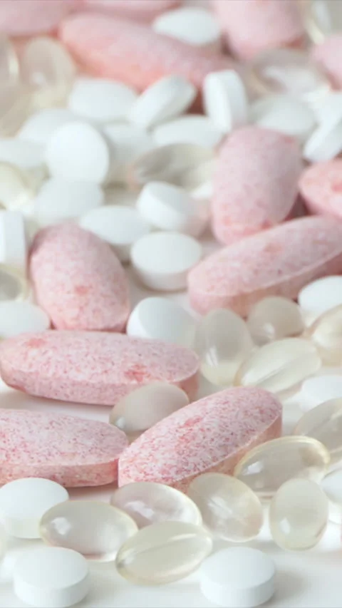 Vertical Screen: Orange, white and omega 3 pills on the table, rotation. Vitamin Stock Footage 232255823