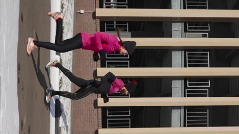 Vertical Screen: Pair jogging around modern building in city Stock Footage 247520368