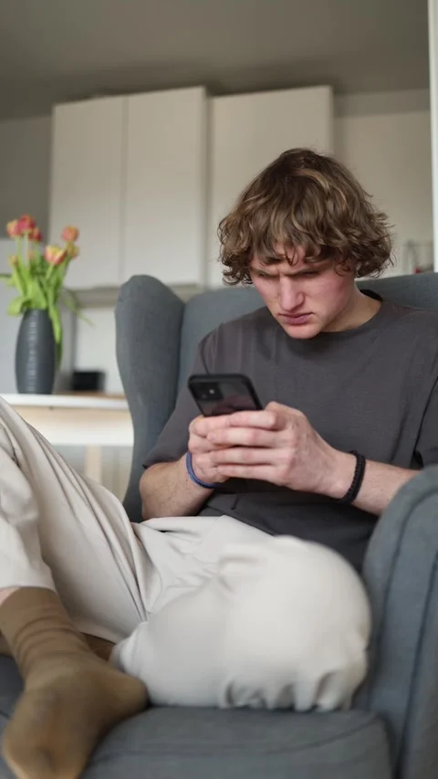 Vertical screen: The person looks focused and slightly concerned while reading s Stock Footage 302632988