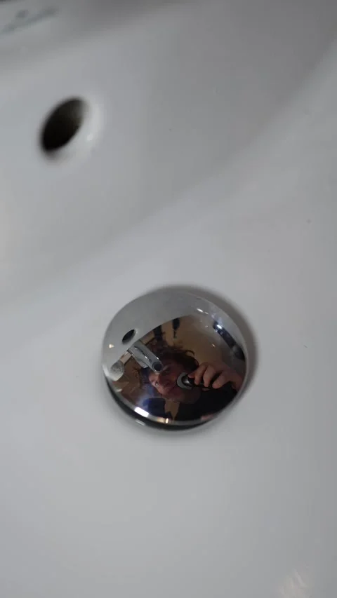 Vertical screen person shaves face in bathroom reflected in chrome drain calm ex Stock Footage 309329685