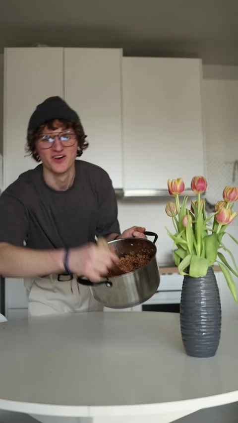 Vertical screen: A person is smiling and holding a pot with a dish, surrounded b Stock Footage 302633399