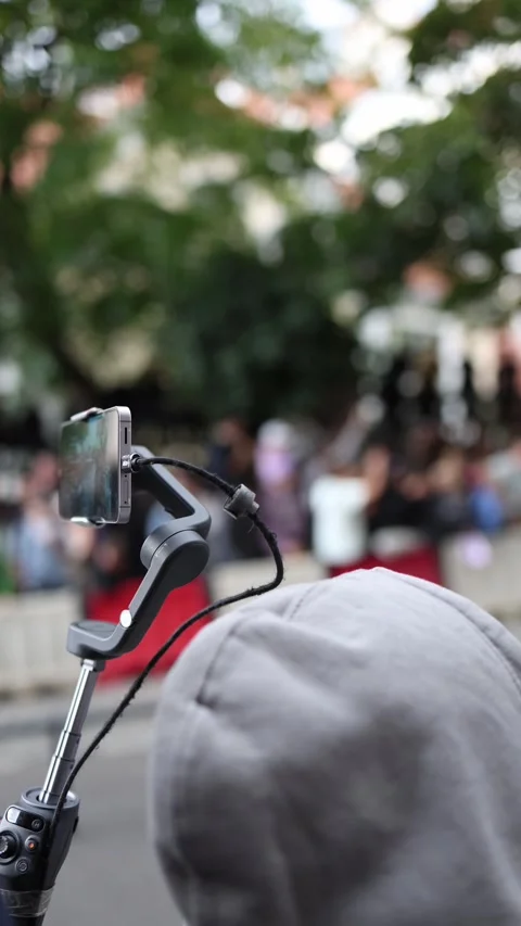 Vertical screen person streaming live on smartphone with stabilizer at outdoor e Stock Footage 315414505
