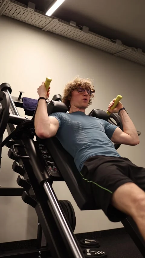 Vertical screen: The person is using a gym machine to work out, focusing on stre Stock Footage 301676789
