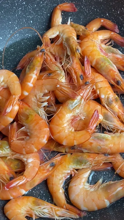 Vertical screen: Professional chef roasts and tosses prawns in black frying pan Stock Footage 237705903