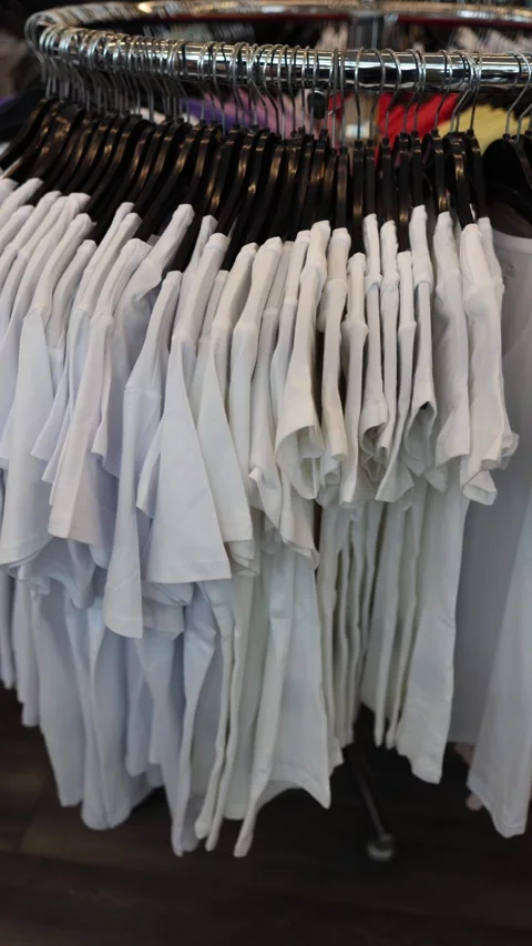 Vertical screen rack of white t shirts neatly arranged on hangers Stock Footage 330014855