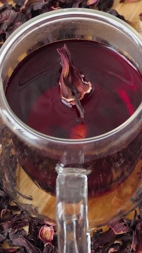 Vertical Screen: Red tea in a glass cup on a white background. Red hibiscus tea Stock Footage 232256017