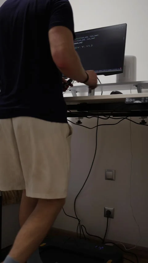 Vertical screen remote employee walks on treadmill while working at computer and Stock Footage 346881579