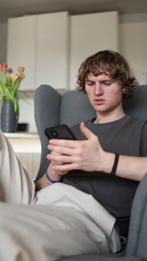 Vertical screen: Restless young man holding smartphone, looking confused and uns Stock Footage 302632368