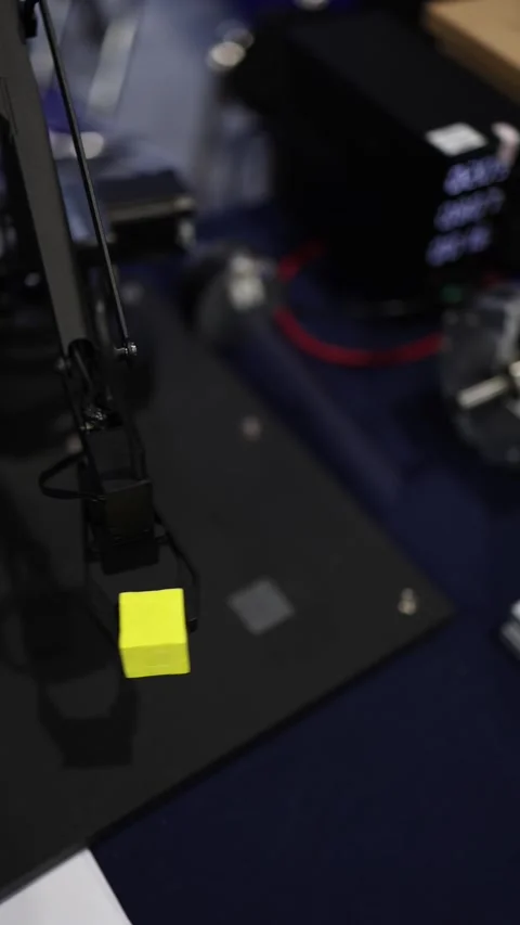 Vertical screen robotic arm with precise gripper lifts small yellow cube in tech Stock Footage 311130417