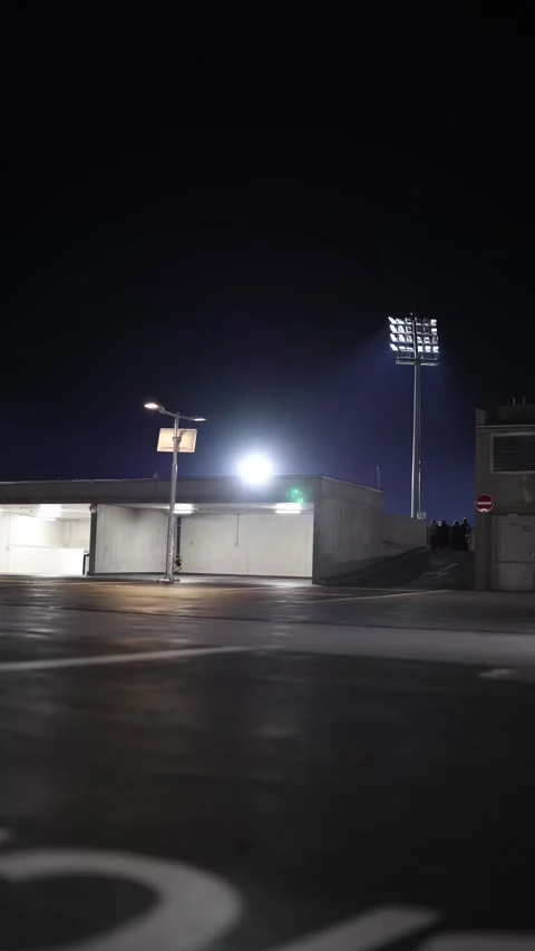 Vertical screen rooftop parking lot at night illuminated by bright stadium flood Stock Footage 314515870