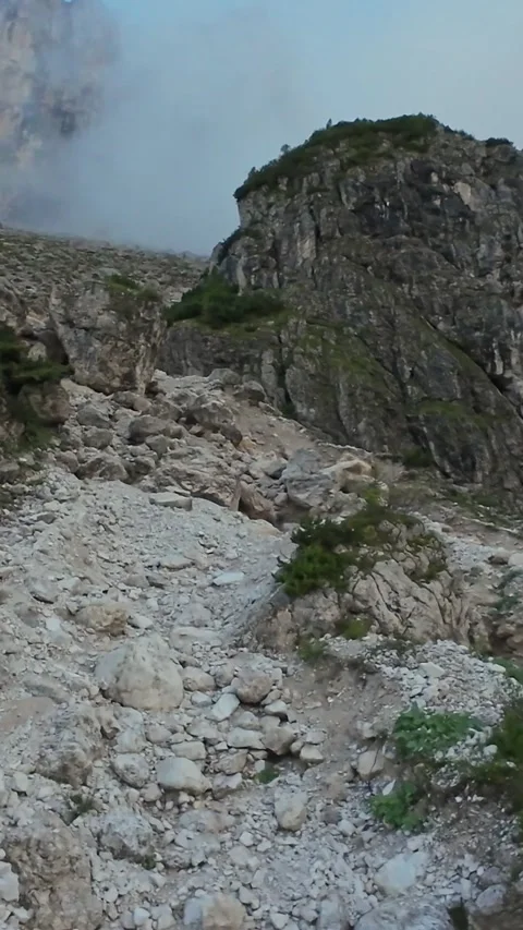 Vertical screen Rugged rocky trail through boulder field under low cloud and Vidéo 323980337