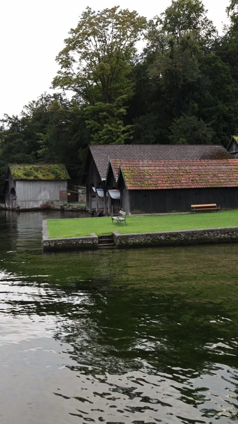 Vertical screen rustic wooden boathouses with red tiled roofs stand by green gra Video stock 318217416