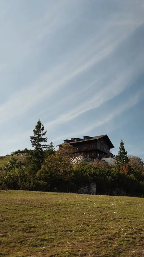 Vertical screen rustic wooden lodge stands on hillside surrounded by evergreen t Stock Footage 318219912