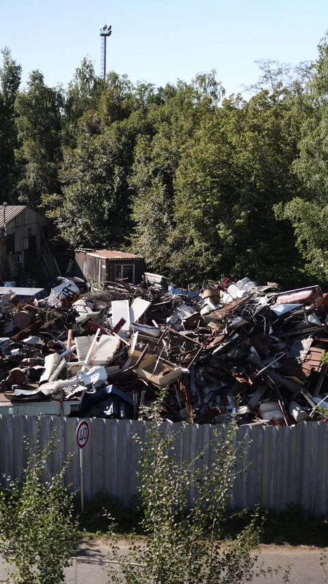 Vertical screen scrapyard filled with piles of metal debris and old machinery be Stock Footage 314823398