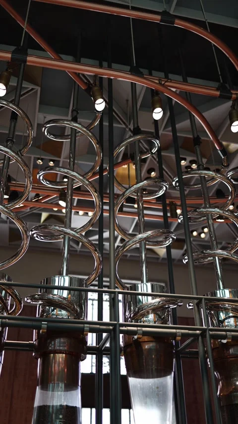 Vertical screen shiny metal spirals swirl above clear coffee bean tubes elegant  Stock Footage 310469897