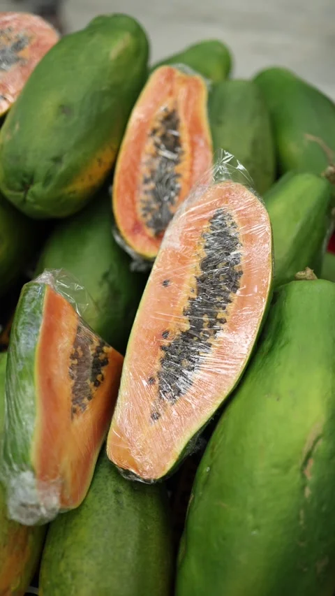 Vertical screen showing a close-up of papayas, with one fruit partially cut open Stock Footage 303285903