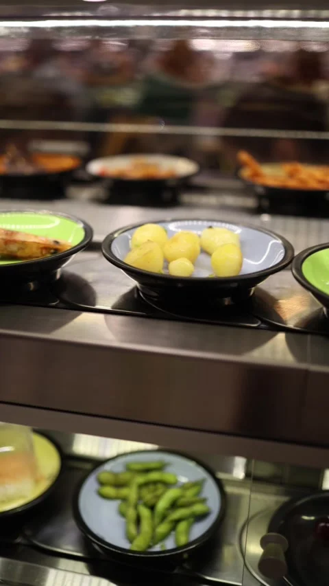 Vertical screen showing a conveyor belt with various dishes such as grilled shri Stock Footage 303285983