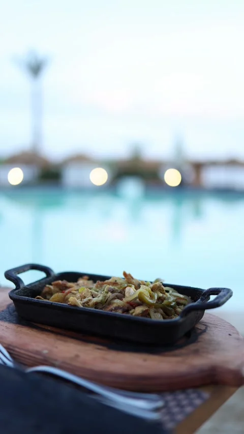 Vertical screen sizzling grilled chicken and veggies served in cast iron on rust Stock Footage 310056328
