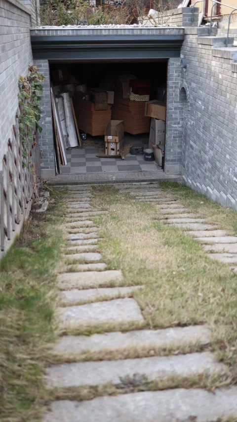 Vertical screen: Sloped driveway with stone steps leading to an open garage fill Stock Footage 304884355