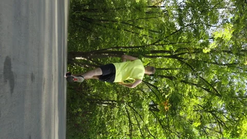 Vertical Screen: Slow motion man jogging in summer park Video stock 253804797