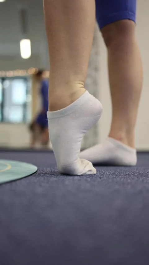 Vertical screen slow warm-up start feet in white socks lift onto toes gentle act Stock Footage 306540690