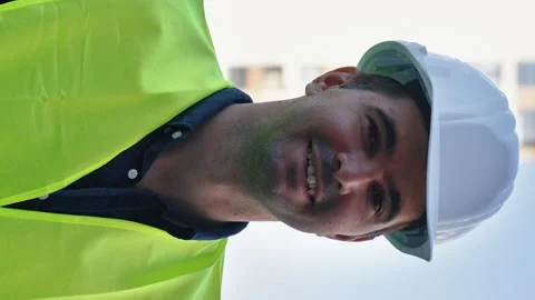 Vertical Screen: Smiling contractor in hard hat against multistory buildings Stock Footage 169162123