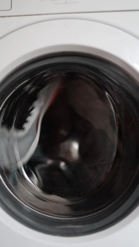 Vertical screen sneakers spin inside a washing machine during a fast cycle with  Stock Footage 313063348