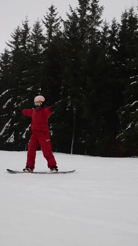 Vertical screen snowboarder rides downhill balancing with raised arm Stock Footage 327092337