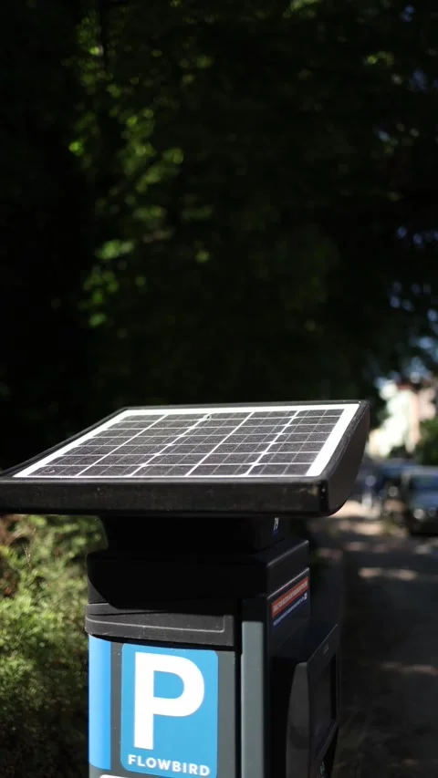 Vertical screen solar-powered parking meter stands on a quiet street under sunli Stock Footage 312315963