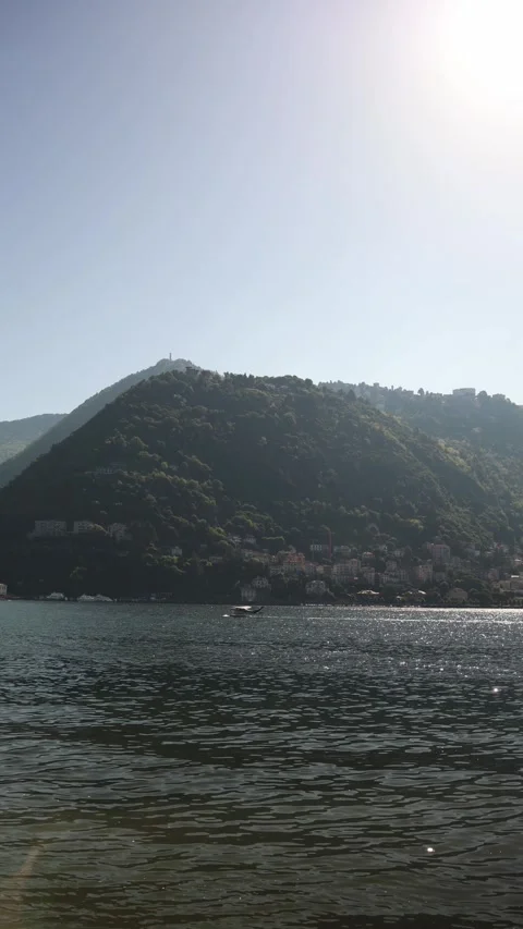 Vertical screen sparkling lake with seaplane taking off near hillside town lush  Stock Footage 310469658