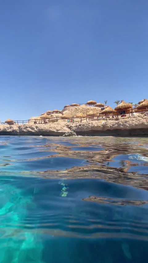 Vertical screen split view shows tropical resort with straw umbrellas and rocky  Video stock 317086576