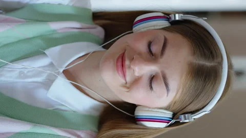 Vertical Screen: Student doing homework and listening to music with headphones Video stock 222917987