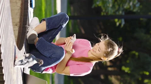 Vertical Screen: Student texting message in park with pigeon Stock Footage 223565122