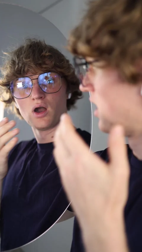 Vertical screen subtle spark of curiosity he studies his reflection with a soft  Stock Footage 313268923