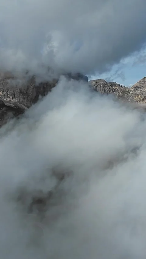 Vertical screen summit peaks peeking through thick fog, mountain guide route Video stock 323575595