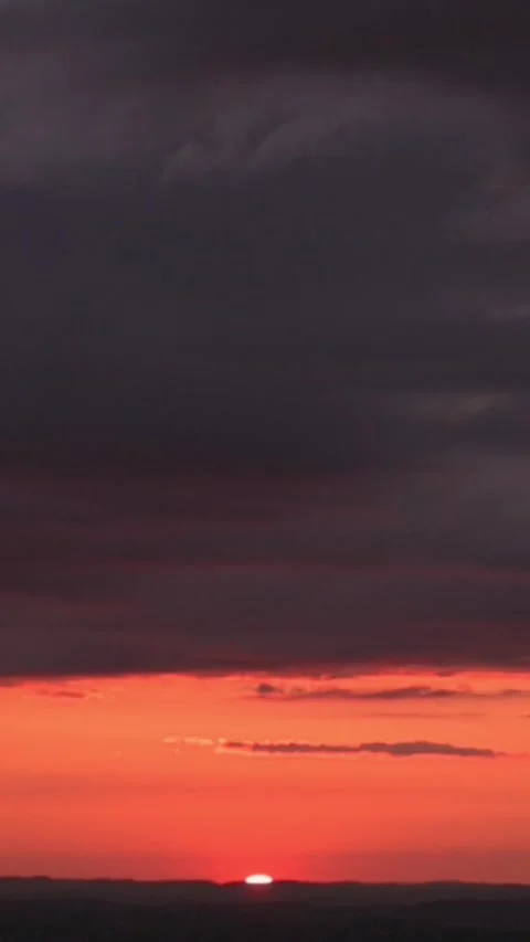 Vertical screen sunset over horizon with crimson sky dark storm clouds roll Vidéo 323242319