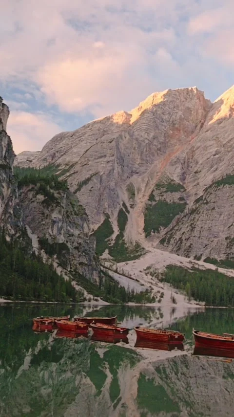 Vertical screen of sunset over Lago di Braies with red boats and dramatic Stockbeeldmateriaal 318384352