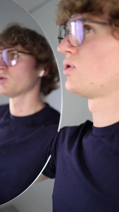 Vertical screen surprised young man stares at his reflection with wide eyes and  Stock Footage 313268872