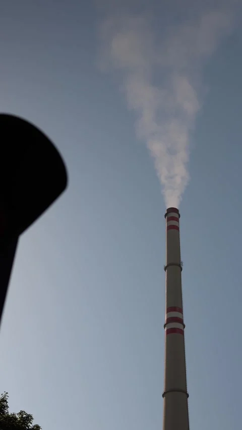 Vertical screen tall industrial chimney with red stripes emits smoke into sky wi Stock Footage 314823335