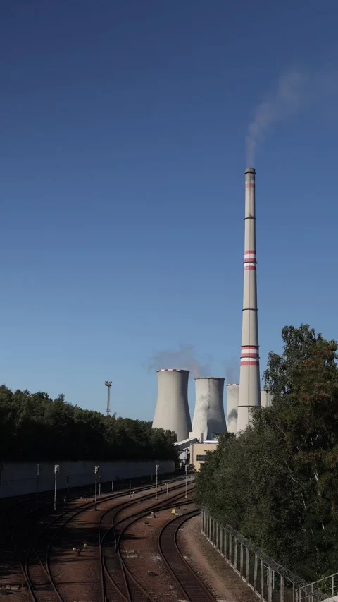 Vertical screen tall industrial chimney with smoke stands beside cooling towers  Stock Footage 314823361
