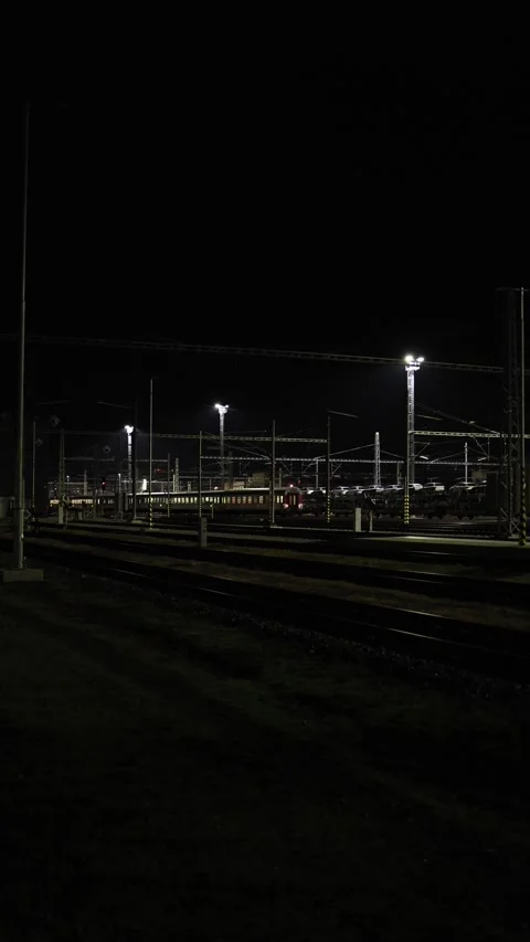 Vertical screen train departs from station in the evening under warm lights crea Stock Footage 319242343