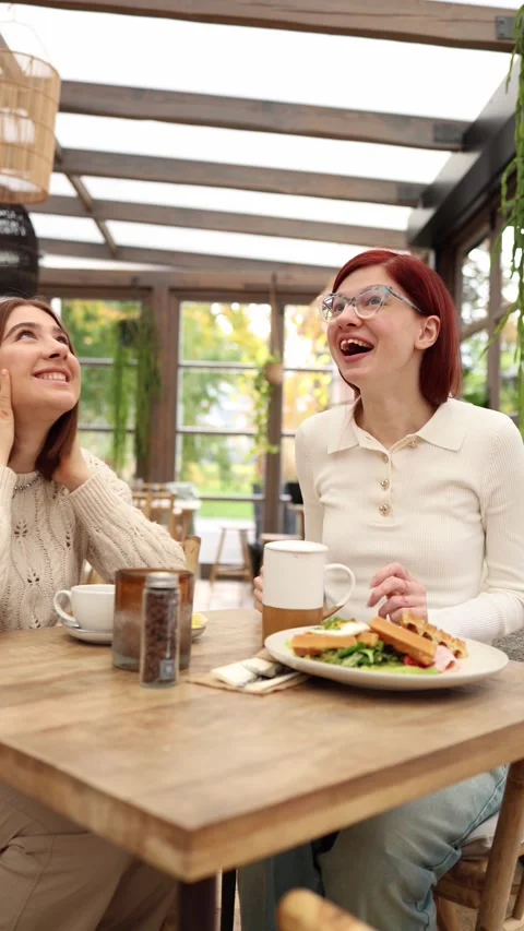 Vertical screen two friends sit in a cozy cafe sharing secrets  Stock Footage 320827153