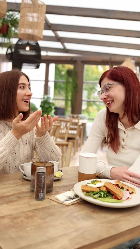 Vertical screen two sisters sit in a cozy cafe talking warmly  Stock Footage 320827146